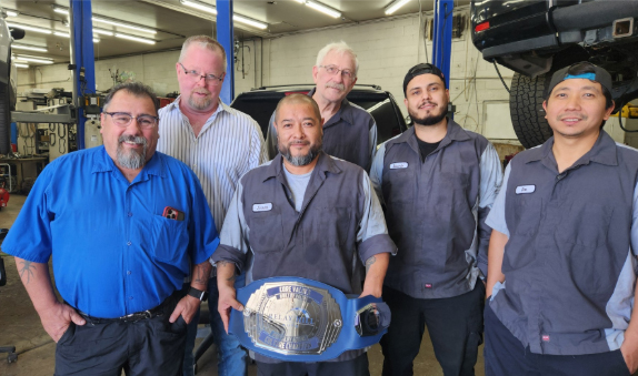 Picture of the team with the champion's belt | Hotchkiss Auto Repair